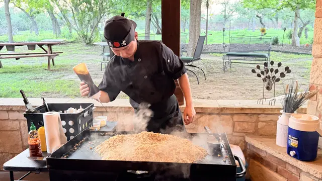 The chef pours sake from a horn over a steaming mound of fried rice